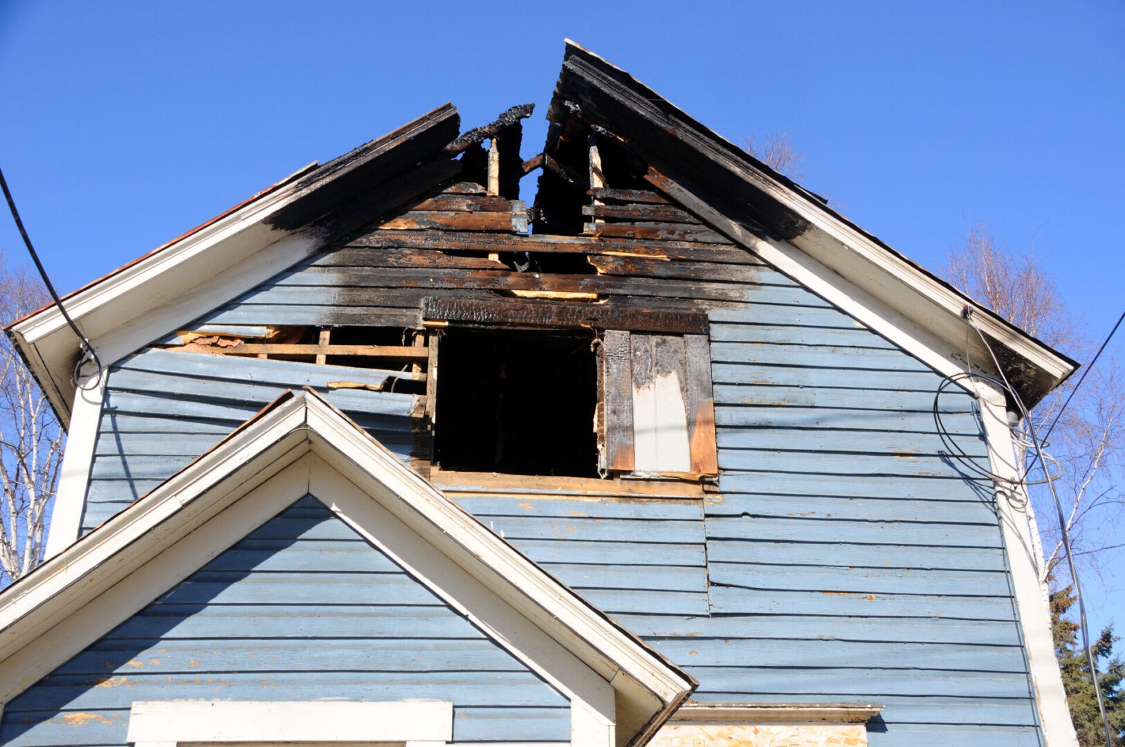 Damaged house roof with charred wooden panels.