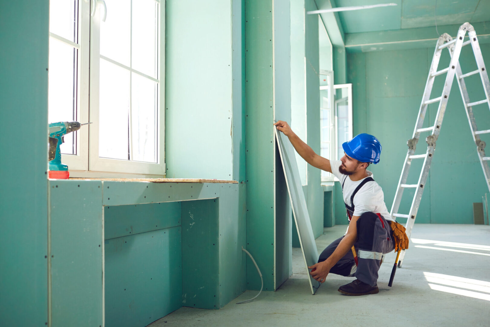 Worker installing drywall in a construction site.